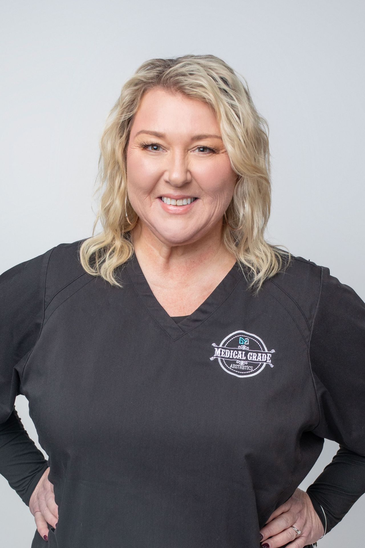 Blonde woman standing smiling at camera with hands on her hips