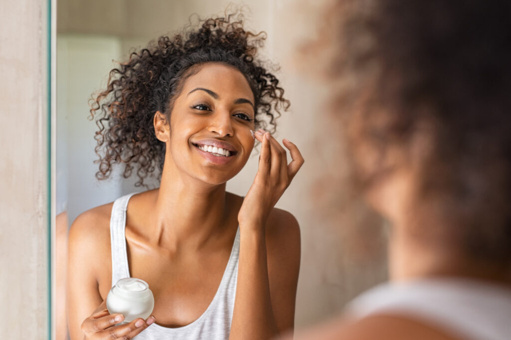 A female patient happily applying her morning skincare after visiting Medical Grade Aesthetics to achieve clear skin with the AviClear laser in Beloit.