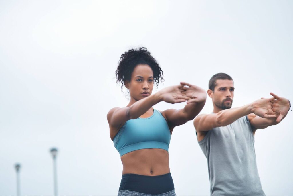 A fit couple stretches together for a workout after completing a session with Emsculpt NEO near Janesville