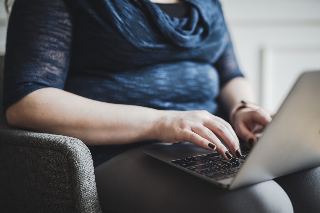An overweight woman at home using her laptop to use the complementary treatment planning tool provided by Medical Grade Aesthetics to see if she is an ideal candidate for weight loss support in Beloit.