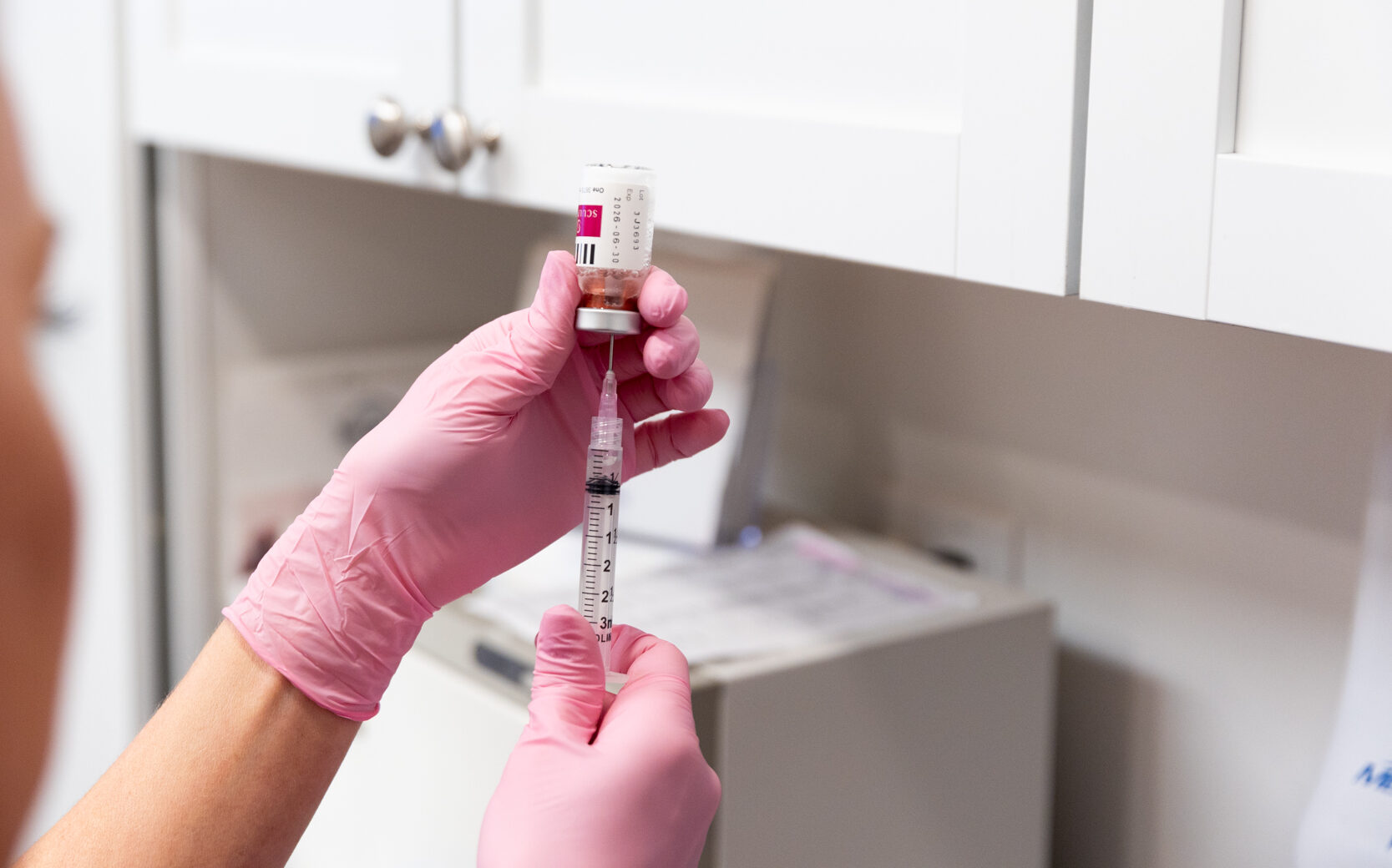 A licensed medical provider prepares a syringe with Sculptra for body contouring near Janesville.